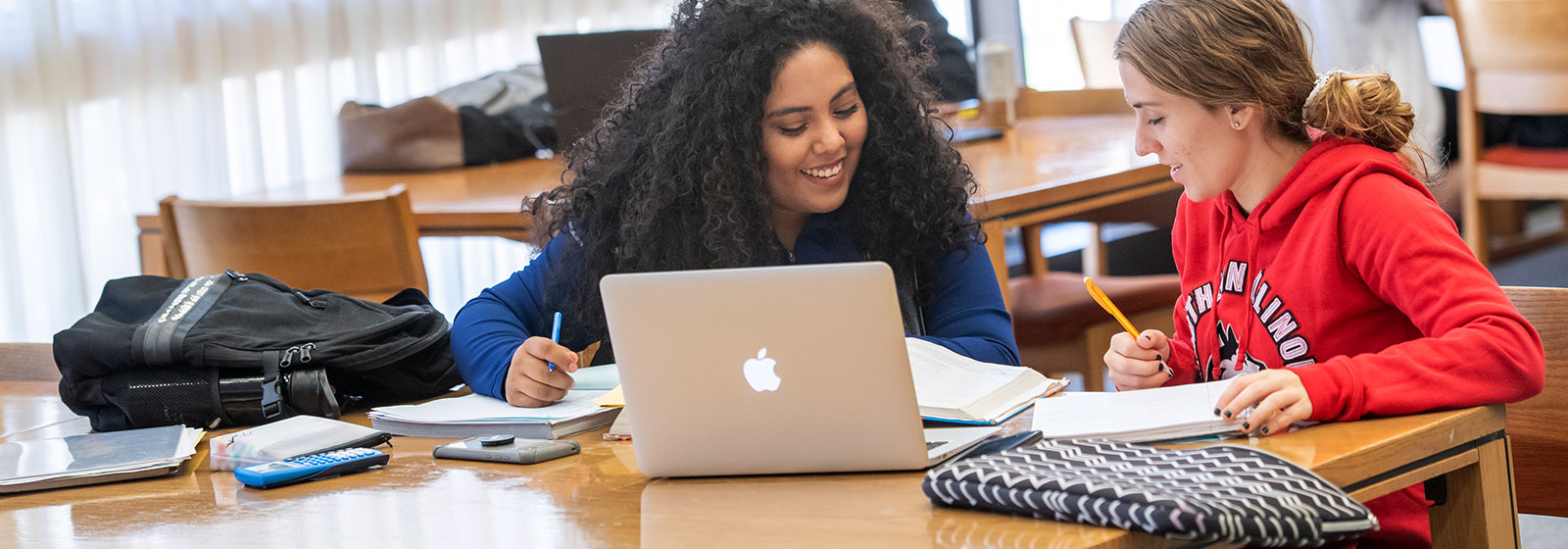 Two students studying together at a table in the library 